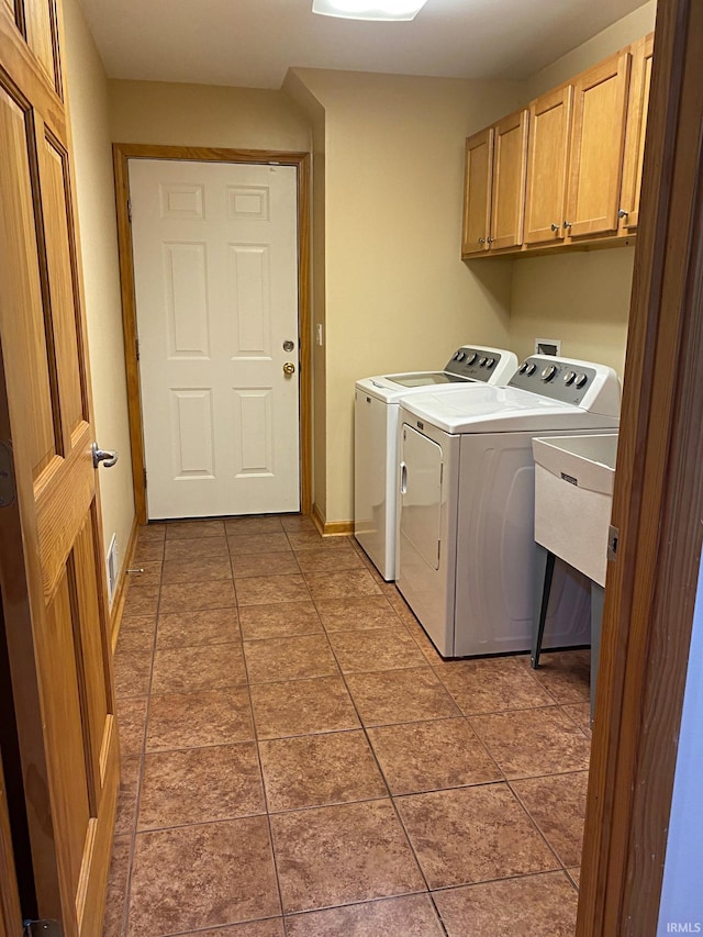 clothes washing area featuring light tile patterned floors, cabinets, washer and dryer, and sink