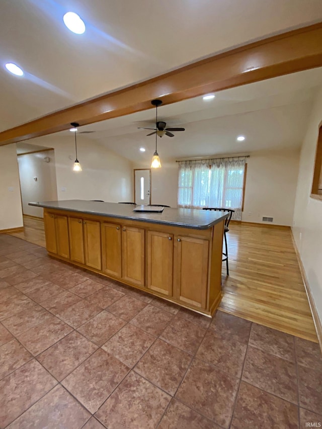 kitchen with hardwood / wood-style floors, ceiling fan, pendant lighting, and a kitchen island with sink