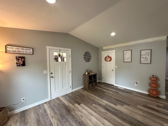 foyer featuring lofted ceiling, dark hardwood / wood-style flooring, and a textured ceiling