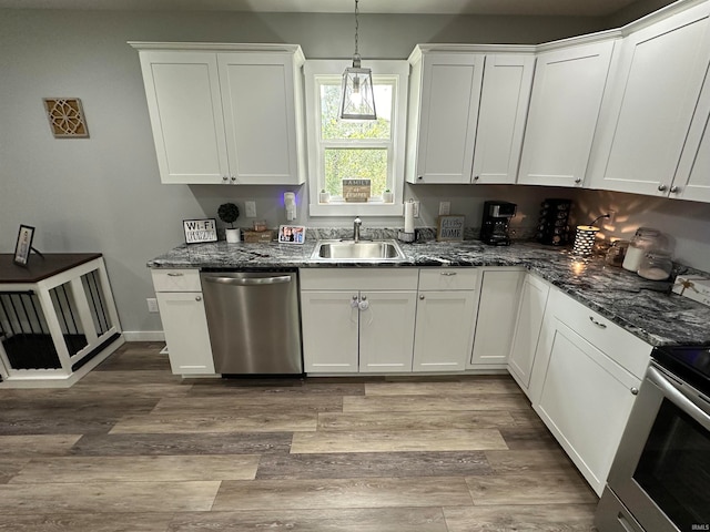 kitchen featuring decorative light fixtures, light hardwood / wood-style flooring, appliances with stainless steel finishes, sink, and white cabinetry