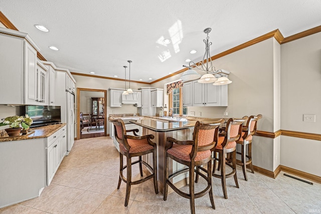 dining room with a textured ceiling, ornamental molding, and light tile patterned floors