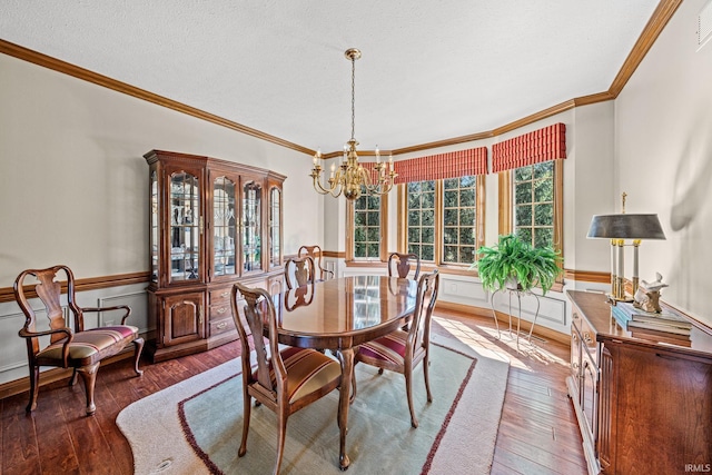 dining space featuring ornamental molding, dark wood-type flooring, a textured ceiling, and an inviting chandelier