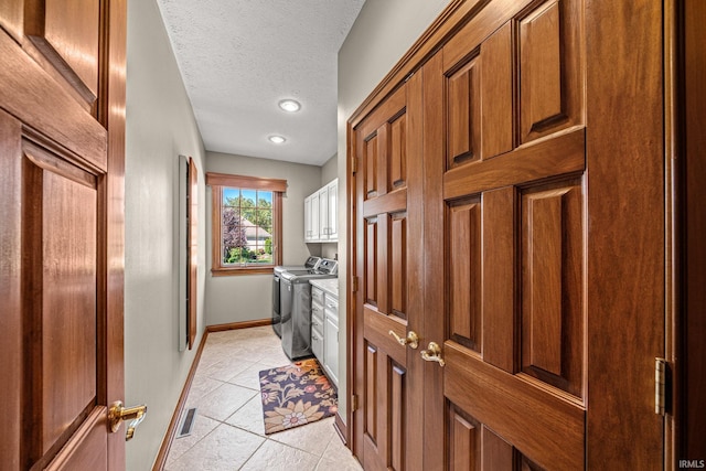 interior space with light tile patterned floors, a textured ceiling, and washing machine and clothes dryer