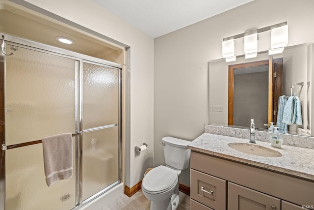 bathroom featuring vanity, toilet, and a shower with shower door