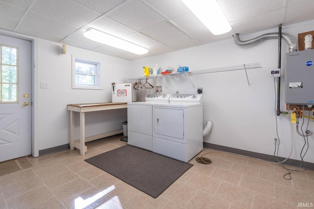 washroom featuring washing machine and dryer, baseboards, and light tile patterned flooring