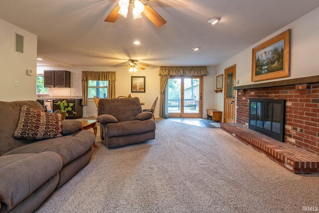 living room featuring carpet, a fireplace, visible vents, and a healthy amount of sunlight