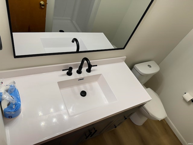 bathroom with wood-type flooring, toilet, and vanity