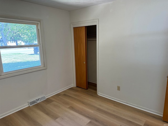 unfurnished bedroom with light wood-type flooring and a closet