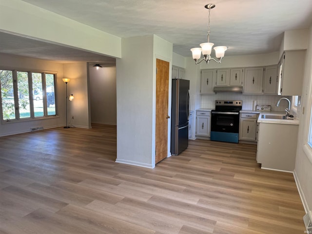 kitchen featuring an inviting chandelier, decorative light fixtures, appliances with stainless steel finishes, sink, and light wood-type flooring