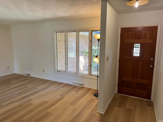 foyer with a textured ceiling and light hardwood / wood-style flooring