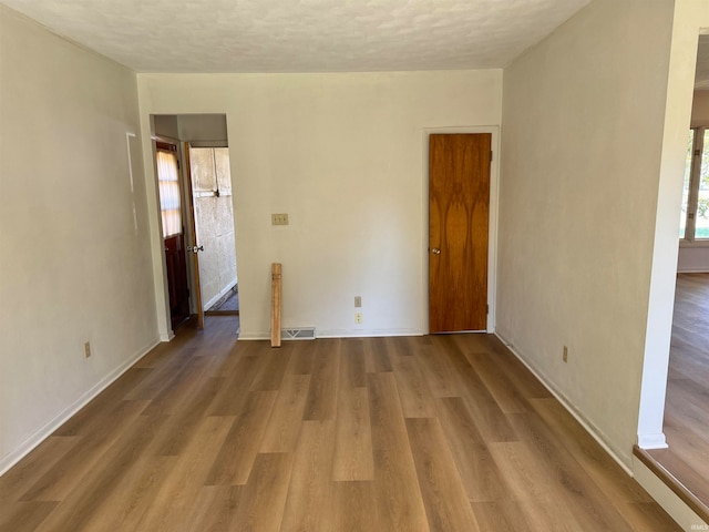 spare room featuring a textured ceiling and light hardwood / wood-style floors