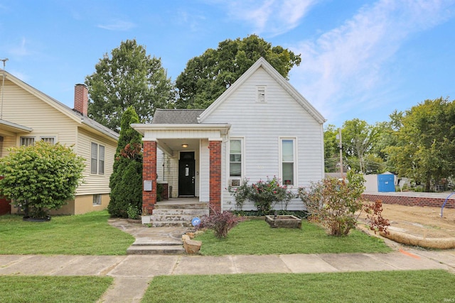 view of front of home with covered porch, a shingled roof, and a front lawn