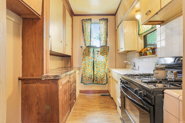 kitchen with visible vents, a sink, black range with gas cooktop, light wood-type flooring, and backsplash