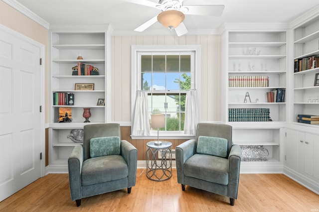 sitting room with built in features, light hardwood / wood-style flooring, ceiling fan, and ornamental molding