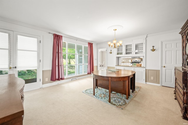 dining area with a chandelier, light carpet, and ornamental molding