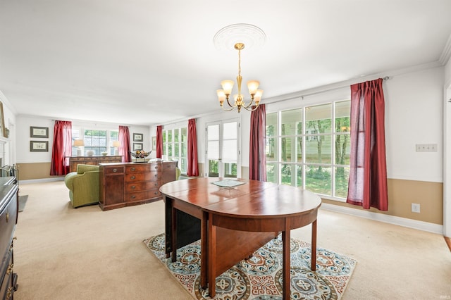 carpeted dining area featuring ornamental molding and an inviting chandelier