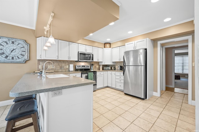 kitchen featuring white cabinetry, stainless steel appliances, kitchen peninsula, sink, and a breakfast bar area