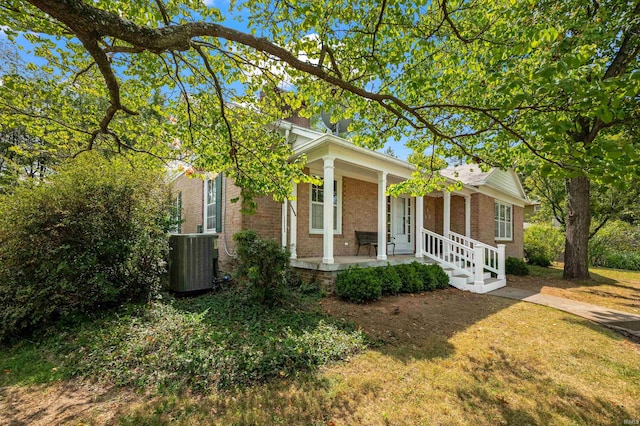 view of front of property with a front yard, covered porch, and central AC unit