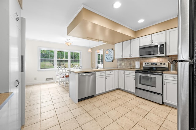 kitchen featuring white cabinetry, kitchen peninsula, stainless steel appliances, and tasteful backsplash