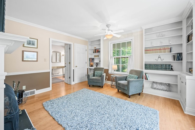 sitting room with built in features, ceiling fan, light hardwood / wood-style floors, and crown molding