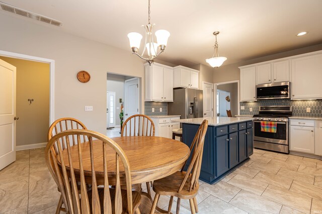 kitchen featuring a notable chandelier, blue cabinetry, white cabinetry, decorative light fixtures, and appliances with stainless steel finishes