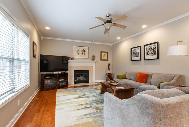 living room featuring light hardwood / wood-style floors, a healthy amount of sunlight, ceiling fan, and a tile fireplace