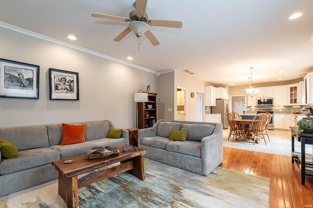 living room featuring ceiling fan with notable chandelier, crown molding, and light hardwood / wood-style flooring