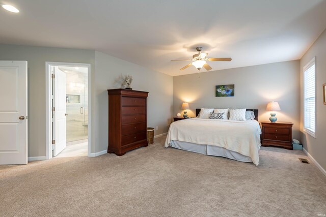 bedroom featuring light carpet, ensuite bathroom, and ceiling fan