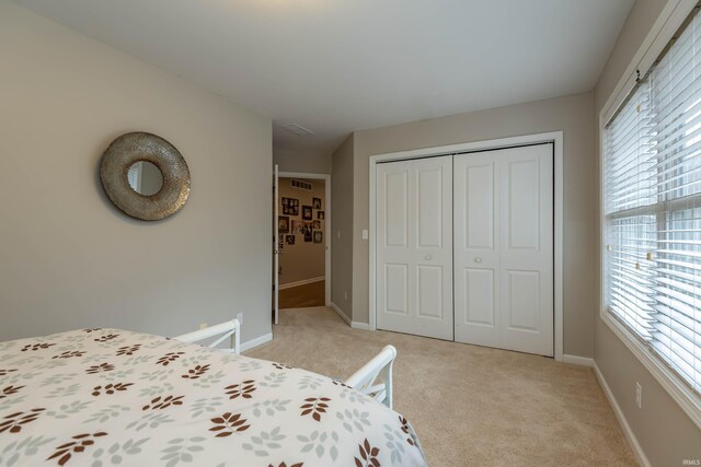 unfurnished bedroom with light colored carpet, a closet, and multiple windows