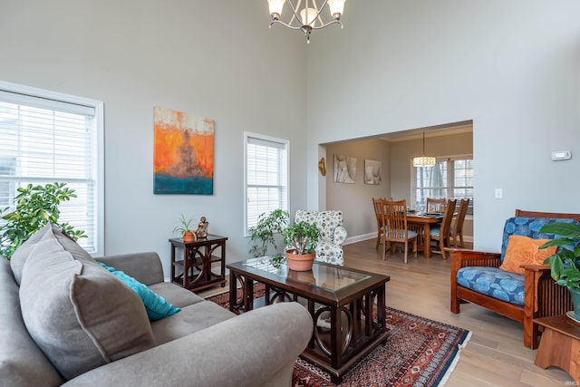 living room featuring a high ceiling, an inviting chandelier, and light hardwood / wood-style floors