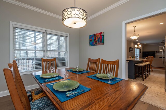 dining room with crown molding, light wood-type flooring, and a notable chandelier