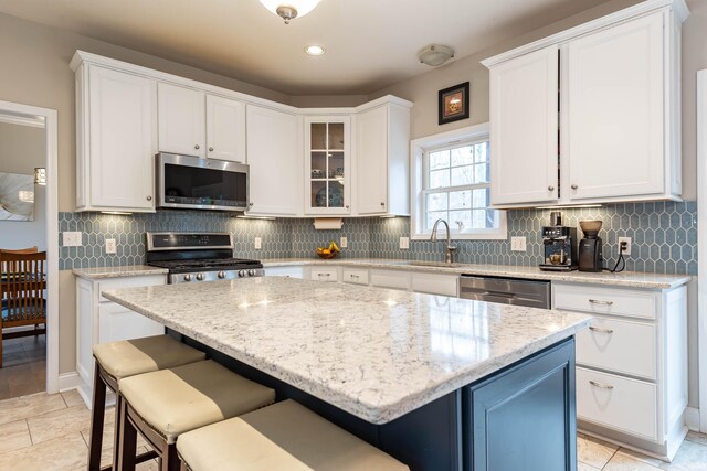 kitchen featuring a kitchen bar, a kitchen island, sink, appliances with stainless steel finishes, and white cabinets