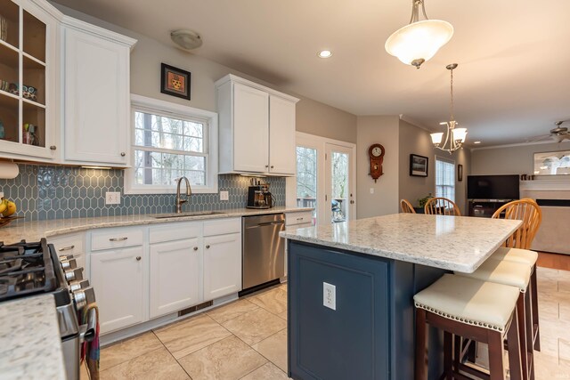 kitchen with white cabinets, hanging light fixtures, stainless steel appliances, and sink