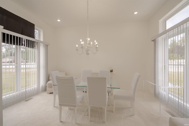 dining space featuring light carpet, a healthy amount of sunlight, and a chandelier