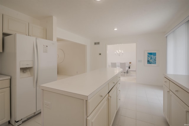 kitchen featuring light countertops, recessed lighting, a kitchen island, white refrigerator with ice dispenser, and a notable chandelier