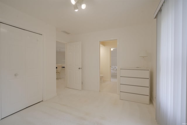 unfurnished bedroom featuring light colored carpet, a closet, and ensuite bathroom