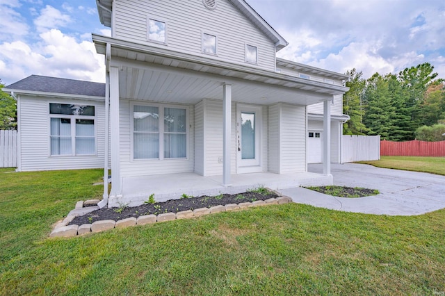 view of front of house featuring a front lawn, a garage, and covered porch