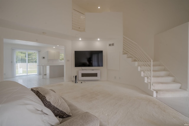 living room with a towering ceiling, a fireplace, and light tile patterned flooring