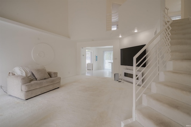 living room with carpet flooring, a towering ceiling, and stairs