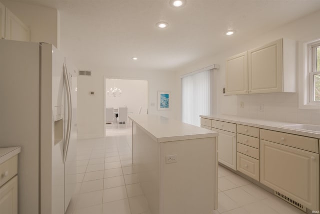 kitchen featuring a notable chandelier, a kitchen island, light tile patterned floors, and white fridge with ice dispenser