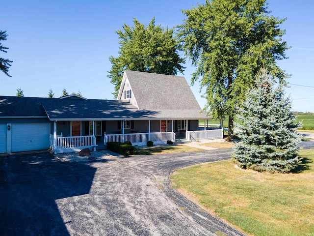 country-style home featuring a front yard, covered porch, and a garage