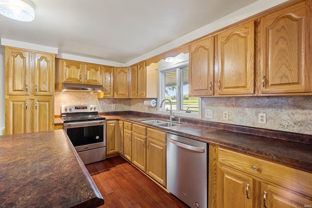 kitchen with appliances with stainless steel finishes, dark hardwood / wood-style flooring, sink, and tasteful backsplash