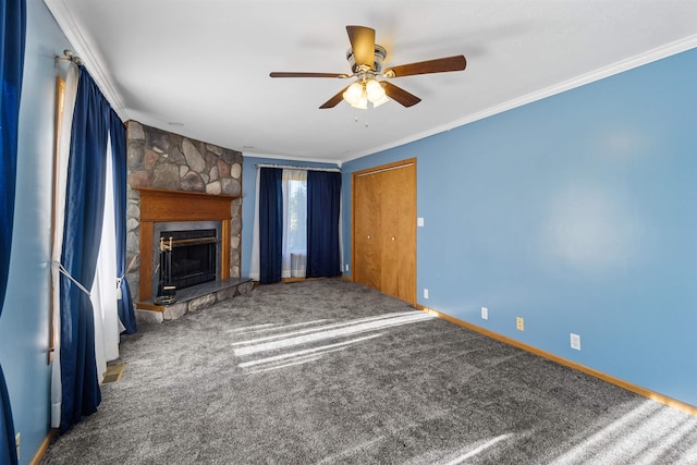 unfurnished living room with crown molding, ceiling fan, a stone fireplace, and carpet