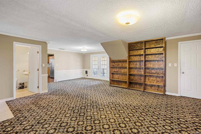 empty room featuring light carpet, crown molding, a textured ceiling, and french doors