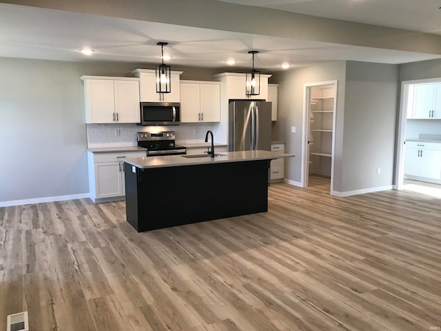 kitchen featuring baseboards, decorative backsplash, light wood-style flooring, appliances with stainless steel finishes, and a sink