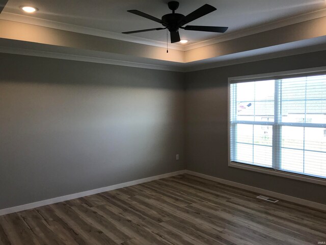 empty room featuring ceiling fan, visible vents, baseboards, dark wood finished floors, and crown molding