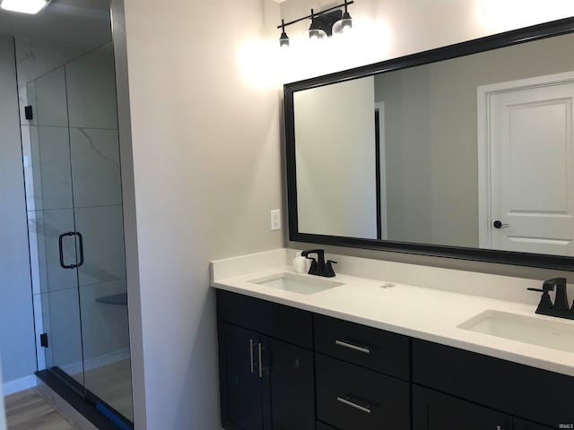 bathroom featuring a stall shower, a sink, and double vanity