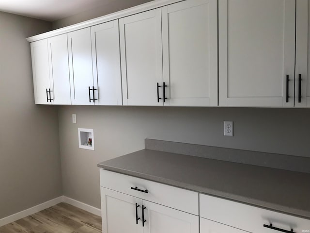 washroom with washer hookup, light wood-type flooring, cabinet space, and baseboards