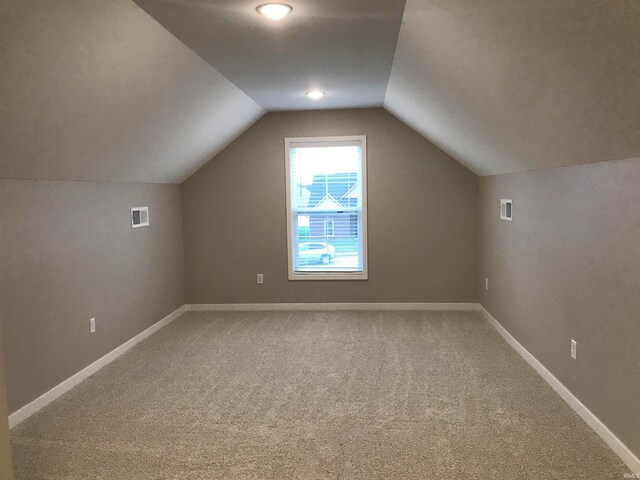 additional living space featuring lofted ceiling, light carpet, visible vents, and baseboards