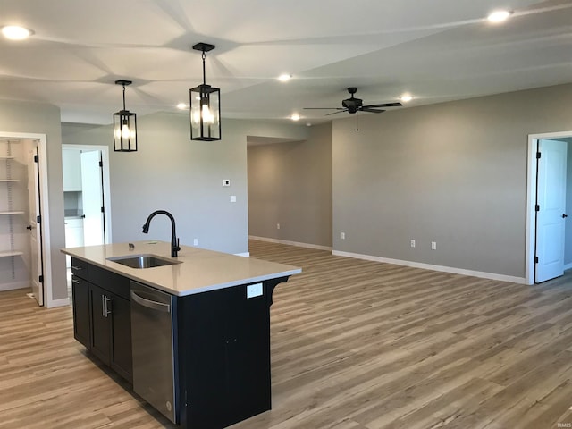 kitchen featuring a center island with sink, light countertops, a sink, dark cabinetry, and dishwasher